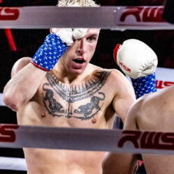 Craig Marshall, il torso coperto di tatuaggi, fra le corde del ring.