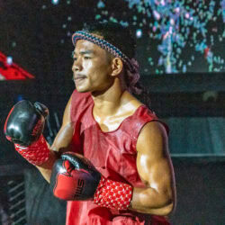 In rosso e con il mongkhon, uno dei due atleti thailandesi nel wai kru prima dell'incontro dei 51 kg.