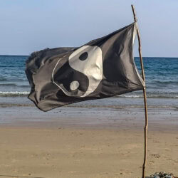 Una bandiera con lo yin e yang piantata nella sabbia, sulla riva di BaanYai.
