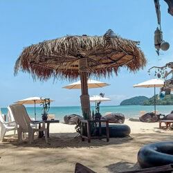Ombrelloni di paglia e sedie sulla sabbia di BaanYai Beach, quasi deserta nei giorni dopo Songkran.